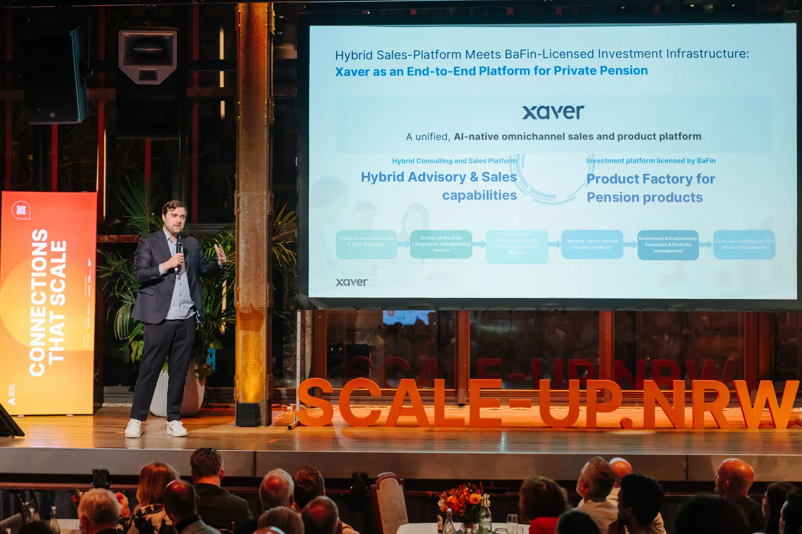 Vortrag auf der Bühne der Scale-up.NRW Full Circle Night, dahinter die Folie „Xaver as an End-to-End Platform for Private Pension“.